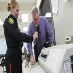 A DUI suspect provides a breath sample into the breath test at the station after being arrested for DUI